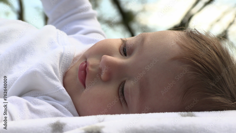 Beautiful adorable cute baby child laid in grass in outdoor exploring discovering world Beautiful adorable cute baby child laid in grass in outdoor exploring discovering world