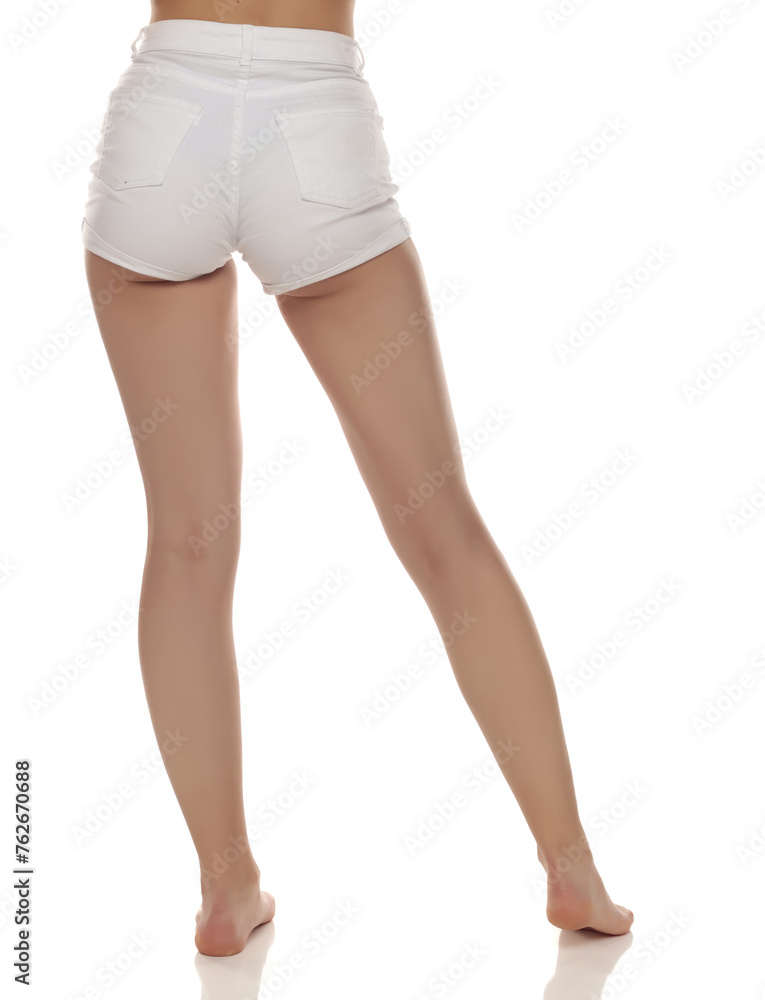 Close up photo of barefoot woman wearing white jeans on white studio background. Rear view.