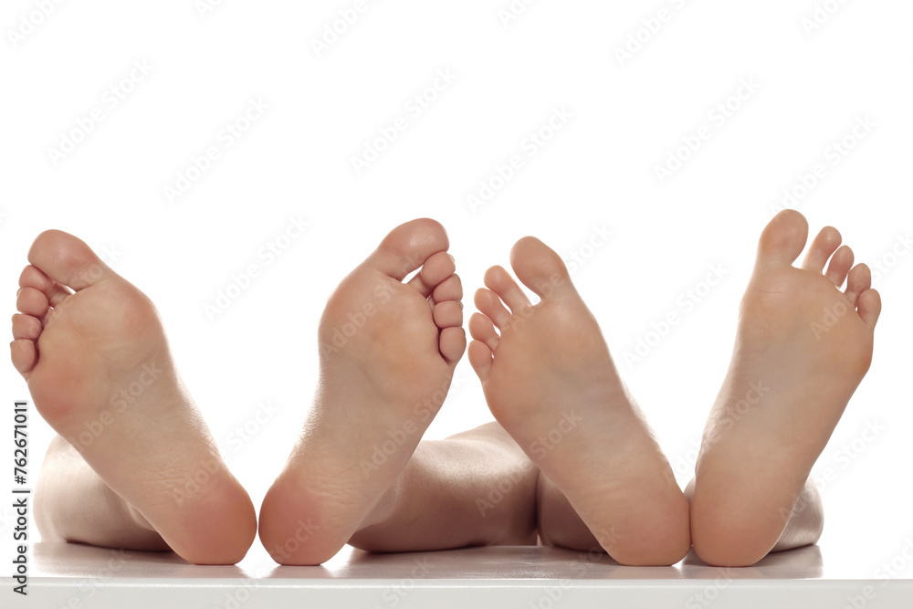 Two pairs od a beautiful well-groomed women's sole feet close-up on a white isolated studio background, The concept of foot skin care. - obrazy, fototapety, plakaty 