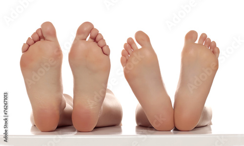 Two pairs od a beautiful well-groomed women's sole feet close-up on a white isolated studio background, The concept of foot skin care.