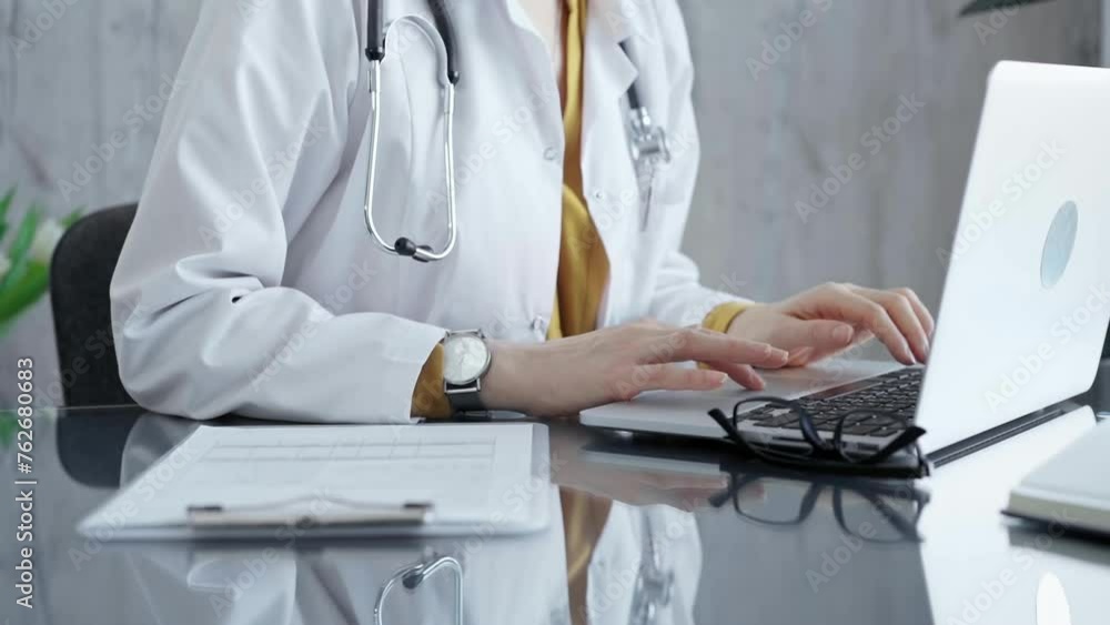 Doctor working on laptop with stethoscope on the glass desk. Medicine and Health care Doctor working on laptop with stethoscope on the glass desk. Medicine and Health care