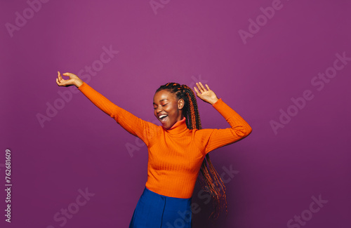 Happy african woman celebrating in colourful casual clothing against vibrant purple background