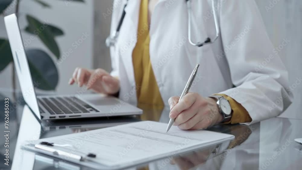 Doctor filling out medical forms while sitting at the glass desk. Doctor filling out medical forms while sitting at the glass desk.