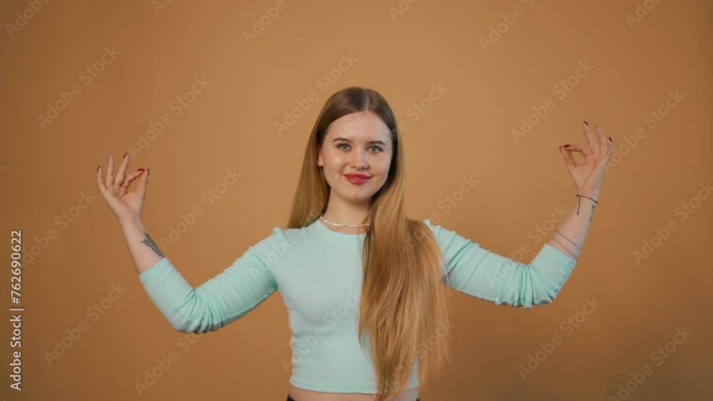 Young woman posing isolated in studio. Smiling cute beautiful adult girl with blond hair shows ok symbol looking camera on grey background in studio. People emotions lifestyle, young beauty concept. Young woman posing isolated in studio. Smiling cute beautiful adult girl with blond hair shows ok symbol looking camera on grey background in studio. People emotions lifestyle, young beauty concept.