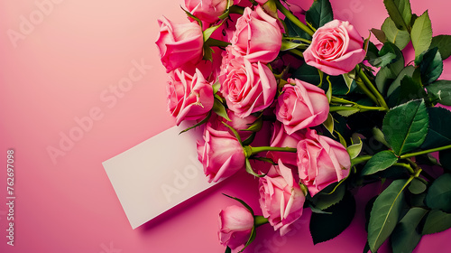 Bouquet of beautiful fresh roses with a card on pink background, top view.