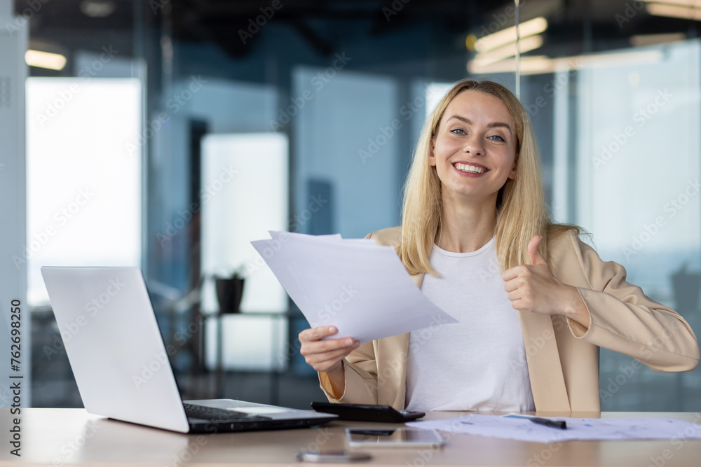 Confident businesswoman reviewing documents in office Confident businesswoman reviewing documents in office
