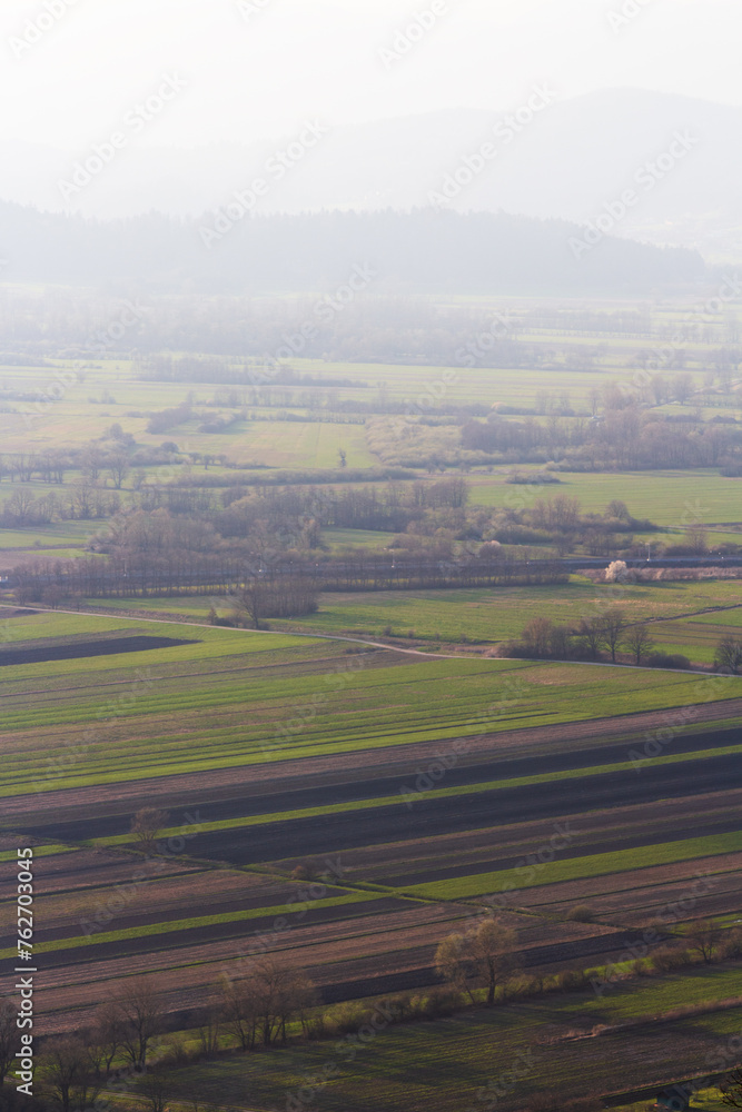 A scenic view over the foggy landscape. An aerial lookout of the fields in the misty valley.