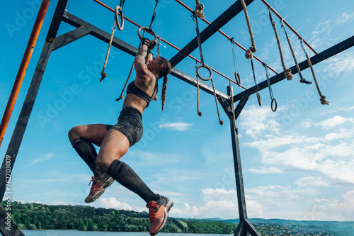 Canvas Print Woman partake in an OCR race while passing the wooden beam with suspensions