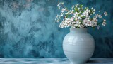  A white vase full of flowers sits atop a table, positioned against a blue and green backdrop
