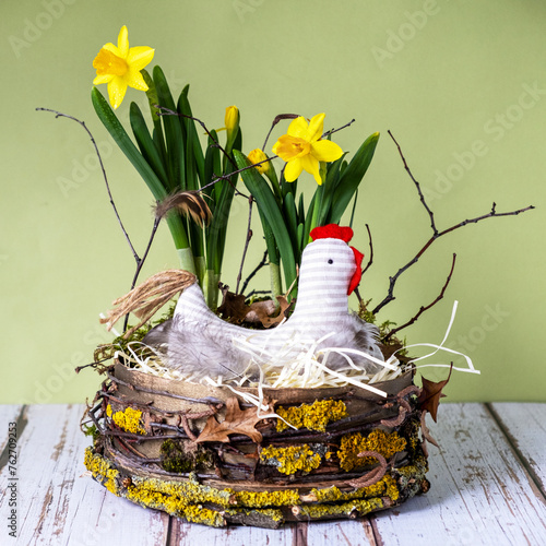 Easter decor in rustic style.Nest, chicken, yellow daffodils on light green background.Handmade.Concept of home comfort and decor on  bright holiday of Easter. Square