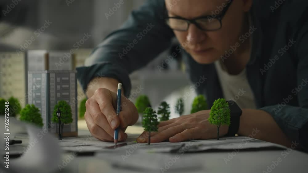 Project. A blueprint designer wearing glasses reviews a design for a new residential area in an innovation office. City of the future innovative approaches to creating green cities Project. A blueprint designer wearing glasses reviews a design for a new residential area in an innovation office. City of the future innovative approaches to creating green cities