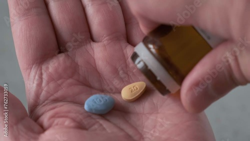 Man takes blue and brown pills in hand medication used to treat erectile dysfunction and prostatitis. Medication for erection. Close up photo