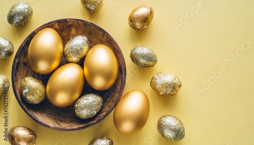 festive easter background with painted golden decoration on easter eggs on pastel yellow table top view and fashion flat lay style