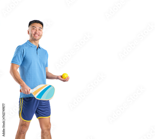 asian boy in shorts and blue polo shirt holding a paddle and pickleball ball on white background