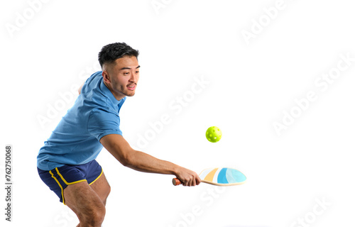 young oriental boy in blue sportswear playing pickleball on white background © Alvaro