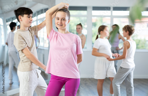 Girl dances Latin dance with male teenager partner during choreography lesson. Group training and rehearsal, preparation for competitions