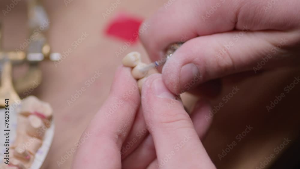 Dentist working with artificial jaw with ceramic crowns polishing in dental laboratory. Dental technician is Checking the chewing motion of the artificial teeth model. Dentist working with artificial jaw with ceramic crowns polishing in dental laboratory. Dental technician is Checking the chewing motion of the artificial teeth model.