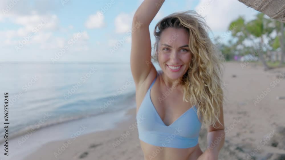 Attractive lady with curly hair, fit body, charming smile winking joyfully, touching palm tree, scenic landscape of the tropical island in the background. High quality 4k footage Attractive lady with curly hair, fit body, charming smile winking joyfully, touching palm tree, scenic landscape of the tropical island in the background. High quality 4k footage