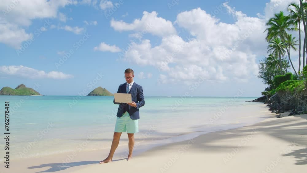Smiling barefoot man in suit, beach shorts with gadget celebrating success, working remotely on Hawaii island, surrounded by ocean, white sand, palm trees. High quality 4k footage Smiling barefoot man in suit, beach shorts with gadget celebrating success, working remotely on Hawaii island, surrounded by ocean, white sand, palm trees. High quality 4k footage