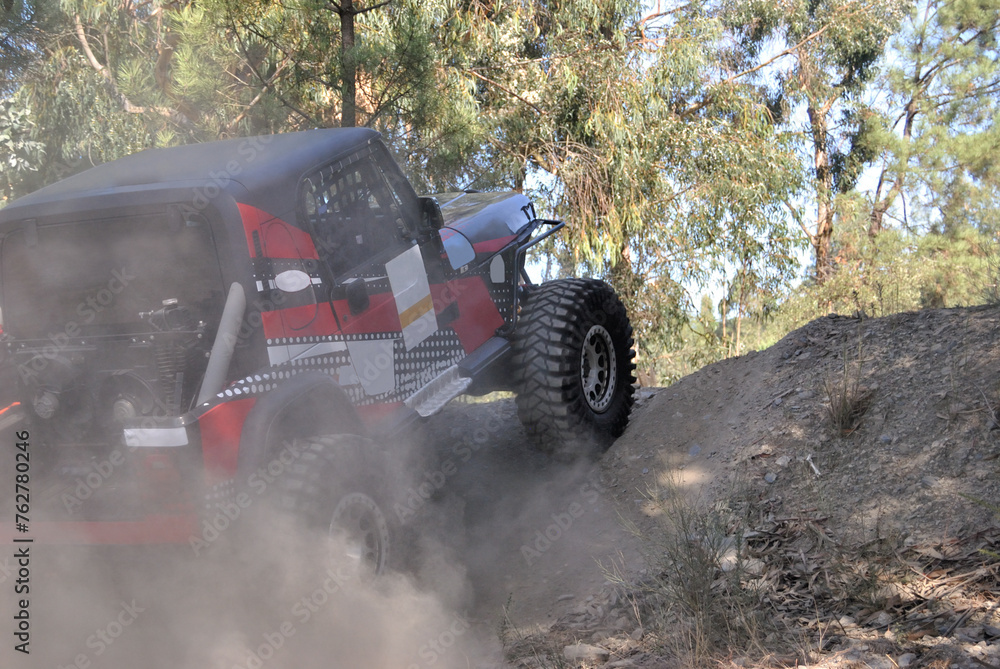 Fototapeta premium Off-road car climbing a dirt ramp on a mountain trail, action and adventure on four wheels