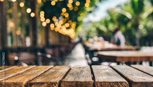 empty brown wooden tables and bokeh lights blurred outdoor cafe abstract background of restaurant lighting where people enjoy eating can be used for montages or to display your products photo