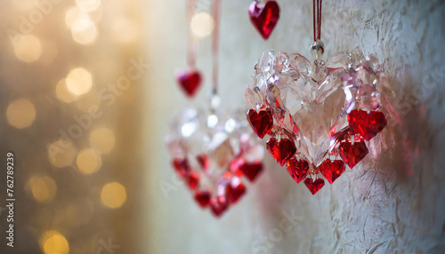 Heart pendants red and pink hanging on the white wall. Elegant glass hearts with sparkling light in the background. photo