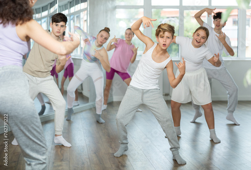 Guy teen performs modern dances repeats movements of unrecognizable teacher together with friends during lesson at choreographic school. Hobbies, active pastime