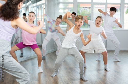 Female teacher performs choreographic exercises and teaches energetic mobile social house dance together with teenagers