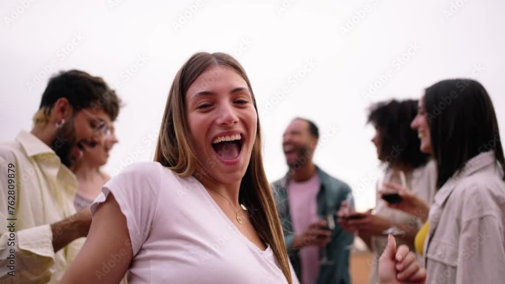 Pretty blonde woman looking flirtatious at camera and dancing with group excited multiracial friends meeting celebrating together with glasses of red wine at penthouse party. People enjoying vacation Pretty blonde woman looking flirtatious at camera and dancing with group excited multiracial friends meeting celebrating together with glasses of red wine at penthouse party. People enjoying vacation
