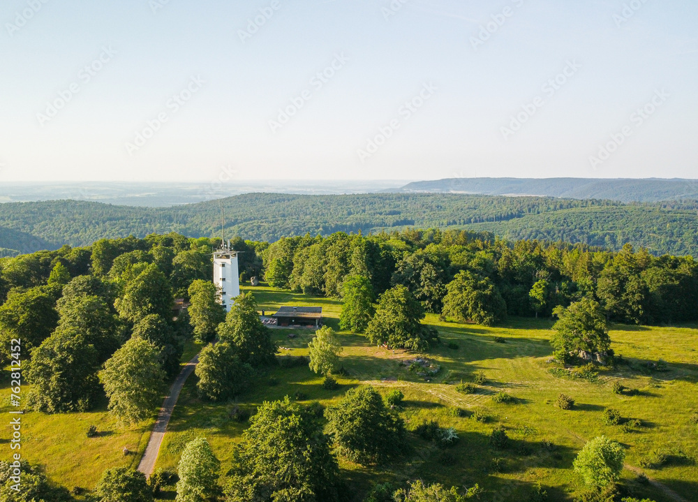 Aerial photo of a white tower in a green forested area. Bavarian forest view. 