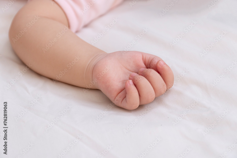 Healthy hand of lovely baby infant sleeping alone on white bed. Small hand fingers body sleep peaceful innocence kid skin lying down on white bed top view. Health care chid Healthy hand of lovely baby infant sleeping alone on white bed. Small hand fingers body sleep peaceful innocence kid skin lying down on white bed top view. Health care chid