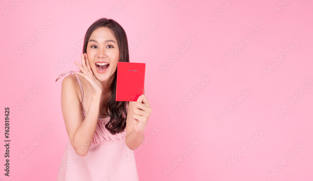 Excited asian traveller woman showing red passport plan vacation holiday toothy smile standing over isolated pink background. Happy young girl pink dresses holding hand beside mouth excited journey. Excited asian traveller woman showing red passport plan vacation holiday toothy smile standing over isolated pink background. Happy young girl pink dresses holding hand beside mouth excited journey.