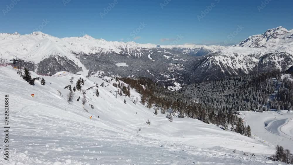 Aerial view of ski slope and skiers skiing down the slope during sunny day during winter holidays Aerial view of ski slope and skiers skiing down the slope during sunny day during winter holidays