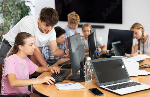 Curious underage girl engaged in IT training with help of teacher in computer courses