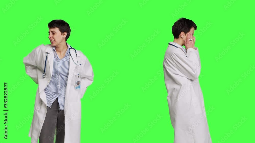 Medic in white coat suffering from migraine and lower back pain, feeling overworked and stressed at hospital. Unwell doctor with headache and spine discomfort against greenscreen backdrop. Camera B. Medic in white coat suffering from migraine and lower back pain, feeling overworked and stressed at hospital. Unwell doctor with headache and spine discomfort against greenscreen backdrop. Camera B.