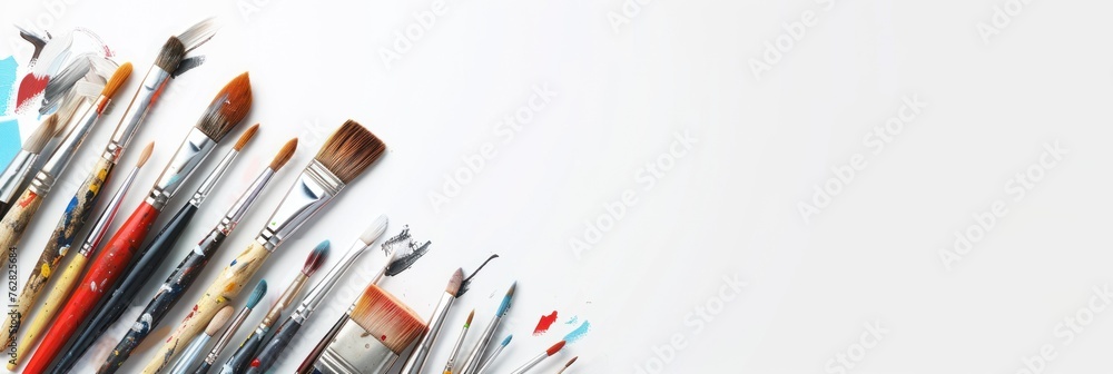 Fototapeta premium On a white surface there are a variety of painting brushes of different sizes and colors.
