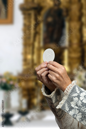 Принти на полотні Priest raising consecrated host during a mass in a church