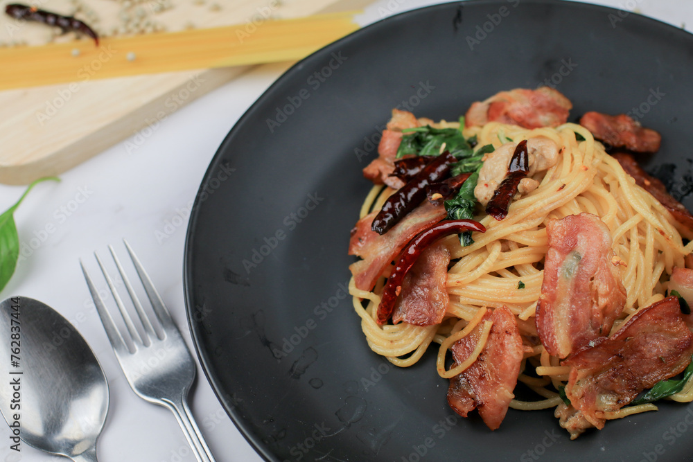 Spaghetti with Dried Chili, basil and Bacon on white table. Traditional Popular menu classic italian cuisine dish. Delicious spicy food. Spaghetti with Dried Chili, basil and Bacon on white table. Traditional Popular menu classic italian cuisine dish. Delicious spicy food.