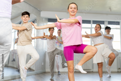 Female girl student repeats movements of unrecognizable teacher during group modern dance class. Hobbies  active pastime  additional extracurricular activities for children and teenagers