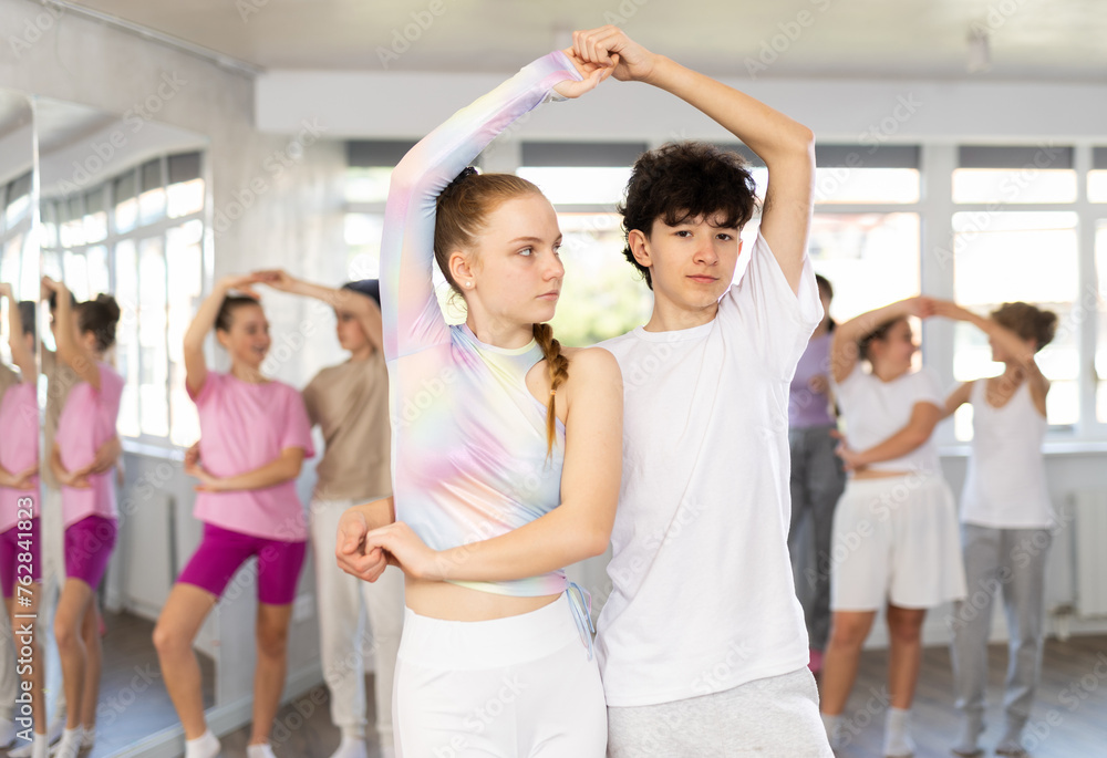 Couple teenagers boy and girl rehearsing pair waltz dance in studio