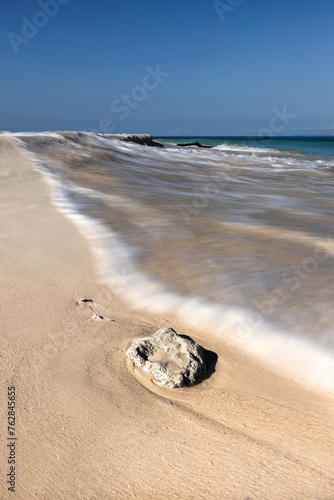 White sand beach, rock, blues skies and a wave at Neil island, Lakshmanpur beach, Andaman islands, India. photo