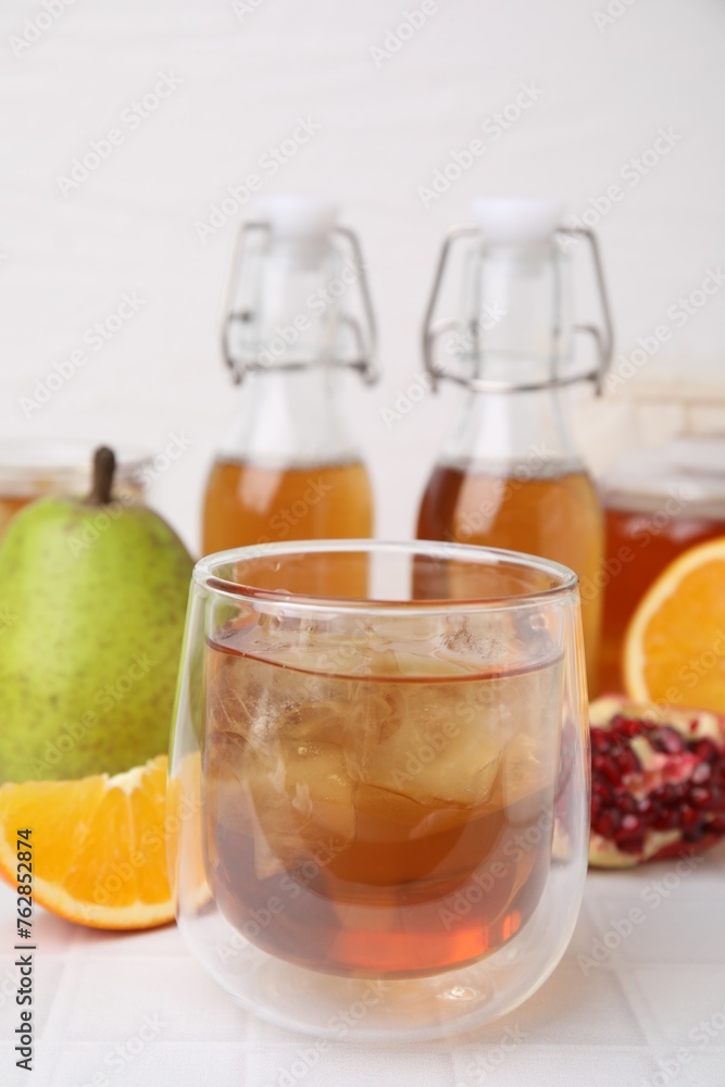 Tasty kombucha with ice cubes and fresh fruits on white tiled table, closeup Tasty kombucha with ice cubes and fresh fruits on white tiled table, closeup