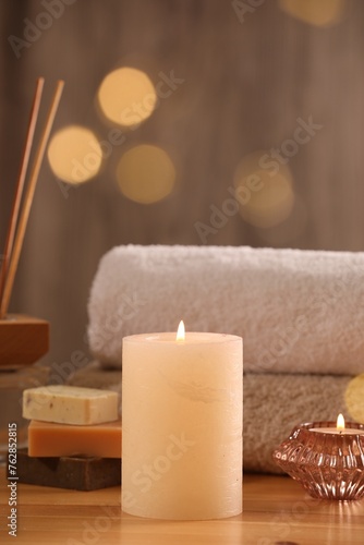 Spa composition. Burning candles, towels and soap on wooden table, closeup