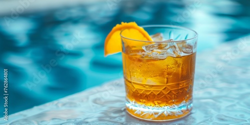 Close-up of a chilled beverage in a textured glass, garnished with an orange slice, against a blurred blue background.