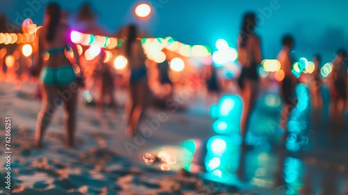 Out-of-focus shot of people enjoying a beach party at dusk with colorful bokeh lights.
