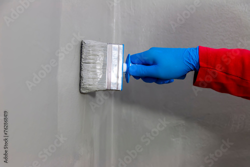 Obraz na plátně A builder worker applying waterproofing paint to the bathroom wall and floor