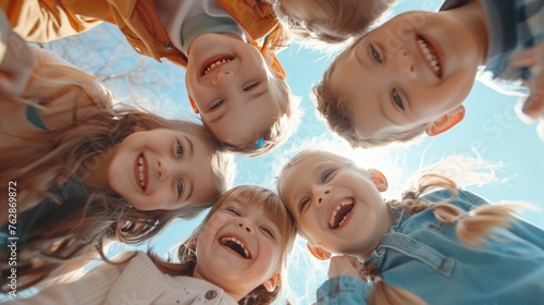 Cheerful joyful cute little children playing together. Group portrait of happy kids huddling. View from below.