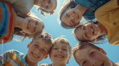 Cheerful joyful cute little children playing together. Group portrait of happy kids huddling. View from below.