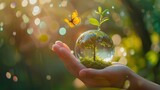 Crystal glass ball of earth and tree growing with sunlight in human hand on blurred background.