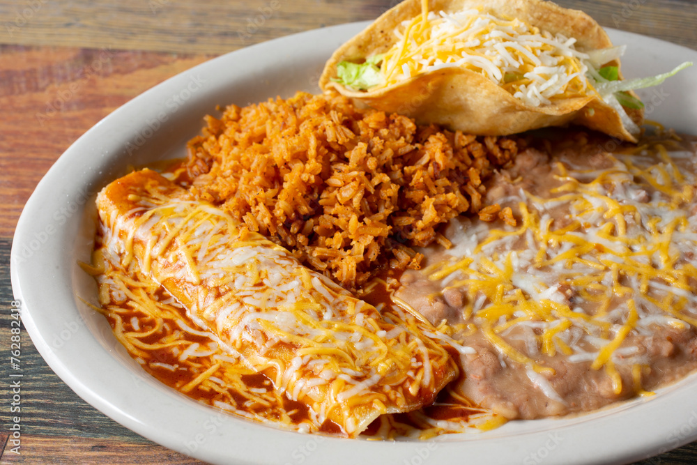 A view of a combo plate, featuring an enchilada, hard taco, rice and beans. - obrazy, fototapety, plakaty 